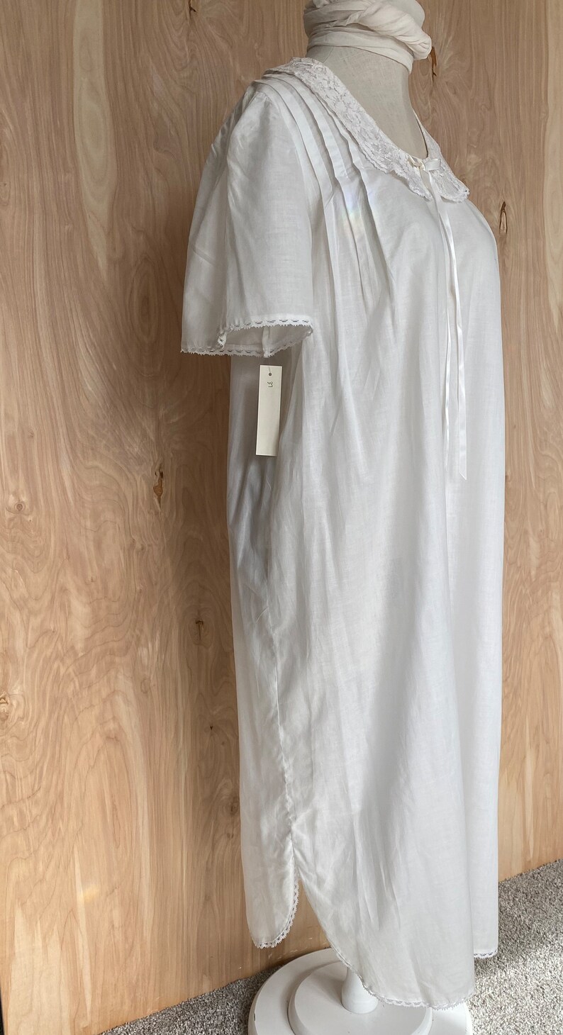 May include: White cotton nightgown with lace trim and a tie at the neck. The nightgown has a tag that says "L" on it.