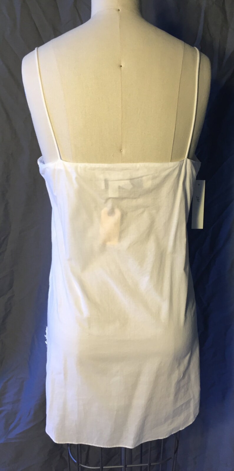 K&ouml;nnte beinhalten: Wei&szlig;es, &auml;rmelloses Schlupfkleid mit d&uuml;nnen Tr&auml;gern. Das Kleid ist aus einem leichten Stoff gefertigt und hat ein schlichtes, klassisches Design.