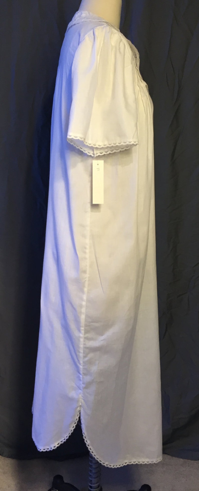 May include: White cotton nightgown with lace trim around the neckline and sleeves. The nightgown has a tag that says "M" on it.