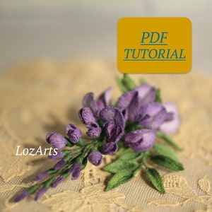 Puede incluir: Un tutorial en PDF para hacer una flor morada con hojas verdes. La flor está hecha de tela y parece realista. La imagen está sobre un fondo de encaje.