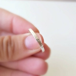 May include: A thin silver band ring with a hammered texture.