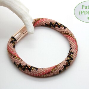 May include: A pink, black and gold beaded bracelet with a magnetic clasp. The bracelet is made with small seed beads and has a geometric pattern.