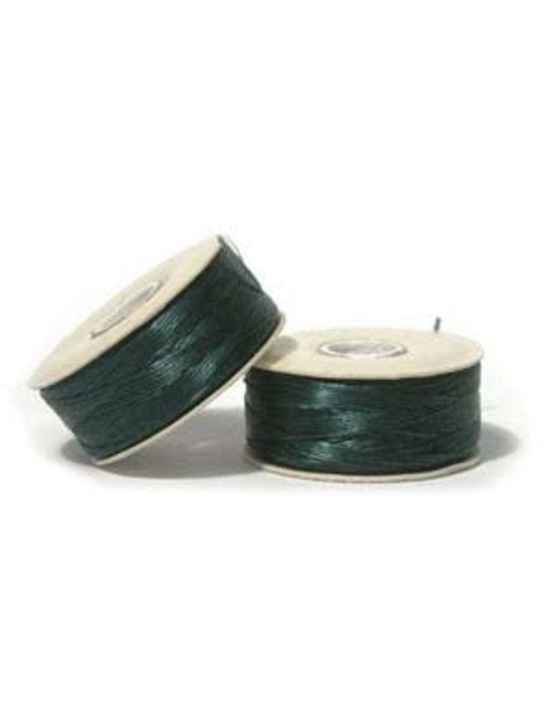 May include: Two spools of dark green thread. The thread is wound around a light-colored cardboard core. One spool is tilted, and the other is upright. The background is white.
