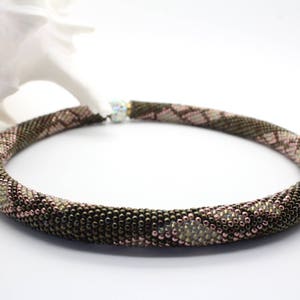 May include: A brown and pink beaded necklace with a snake skin pattern.