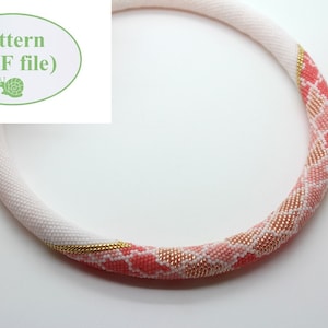 Op de afbeelding: Een kralenketting met een wit en roze gradiëntontwerp. De ketting heeft een patroon van roze en gouden kralen, met een witte basis. De afbeelding bevat ook een groene ovaal met de tekst "Pattern (PDF file)".