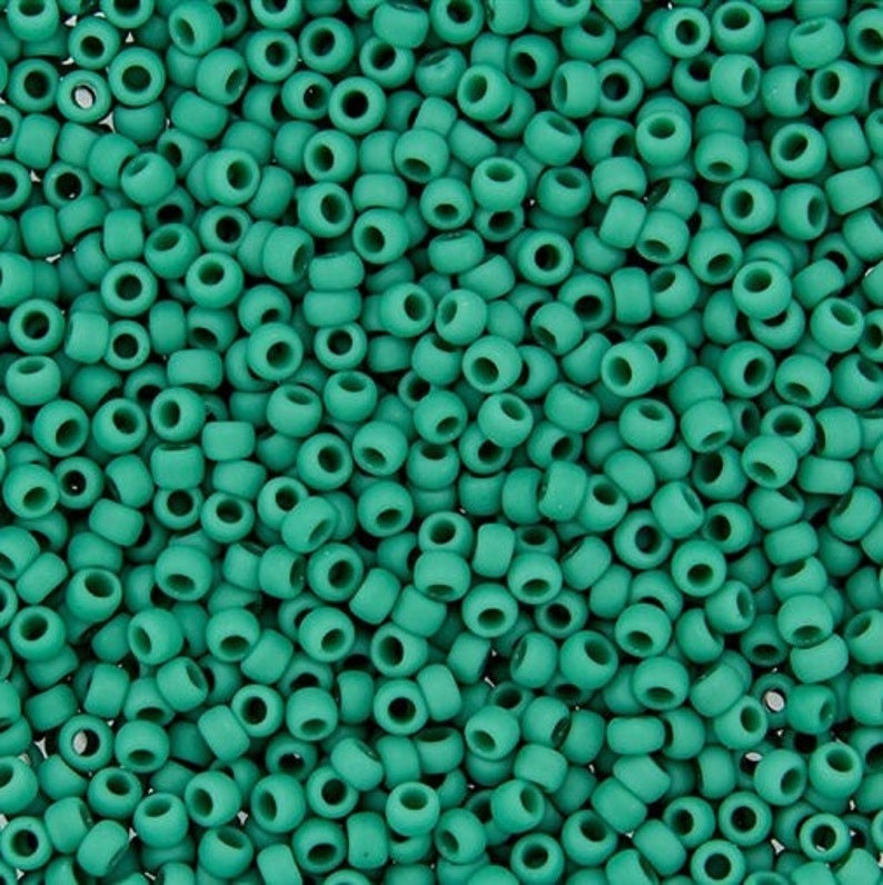K&ouml;nnte beinhalten: Eine Nahaufnahme von einer gro&szlig;en Menge an tealgr&uuml;nen Perlen. Die Perlen sind klein und rund und alle gleich gro&szlig;.