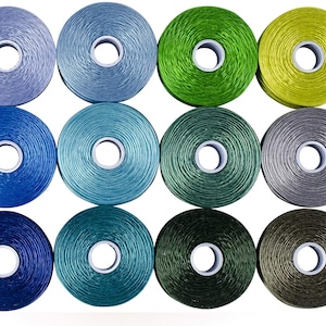 May include: Twelve spools of thread in various colors, including blue, green, and gray. The spools are arranged in a grid pattern on a white background.
