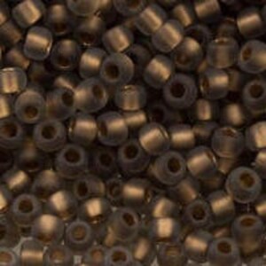 May include: A close-up of a pile of small, dark brown glass seed beads. The beads have a matte finish and are slightly iridescent.