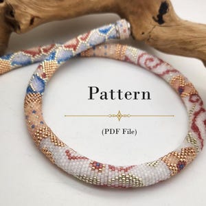 Op de afbeelding: Een buisvormige kralenketting met een veelkleurig geometrisch en bloemmotief in tinten wit, blauw, rood en metallic goud. De afbeelding bevat de tekst Pattern (PDF File) gecentreerd binnen de cirkelvormige omtrek van de ketting.