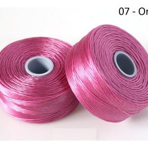 Pode incluir: Dois carret&eacute;is de fio de bordar rosa, etiquetados como "07 - Orchid".
