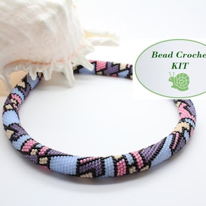 May include: A bead crochet kit for making a necklace. The necklace is made with blue, pink, purple, and black beads. The kit includes all the beads and instructions needed to make the necklace. Bead Crochet KIT.