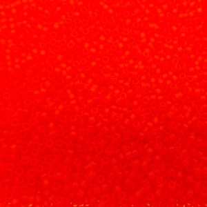 May include: A close-up image of a large quantity of small, round, red beads. The beads are opaque and have a slight shine.