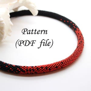 Op de afbeelding: Een zwarte en rode kralenketting met een verloopmotief. De ketting is gemaakt van kleine kralen en heeft een ronde vorm. De tekst "Pattern (PDF file)" staat in het midden van de afbeelding.