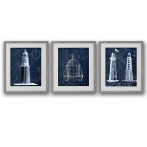 May include: Set of three framed prints featuring vintage nautical blueprints of lighthouses. The prints are in shades of blue and white and are framed in a simple grey frame.