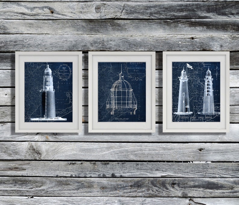 May include: Three framed prints of vintage nautical lighthouse blueprints in shades of blue. The prints feature detailed drawings of lighthouses with text labels including "Colony Massachusetts Bay" and "Sandy Hook Light Vessel"