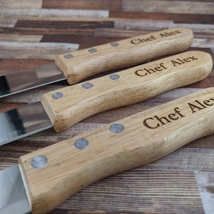 May include: Three wooden-handled kitchen knives with silver blades. Each handle is engraved with the text "Chef Alex".