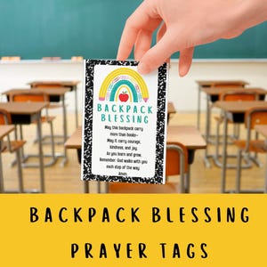 May include: A rectangular prayer tag with a rainbow and apple design, held in front of a classroom setting. The tag reads "Backpack Blessing" with a prayer. The bottom of the image says "Backpack Blessing Prayer Tags".