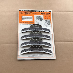 May include: A card with a set of five silver metal "Goody" aluminum wave clips. The card is white with black and orange text. The text reads "For smart and lasting waves. The "Goody" Aluminum Wave Clip. Medium Size. Pinches ridges tightly and gives your waves that professional touch. Ideal for setting permanents. See instructions on reverse. Simple as A. B. C. This is the Medium Size. Also obtainable in Long and Small sizes. A Goody Product. Made in U.S.A. Pat. No. 2040807."