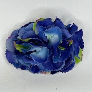 May include: An artificial flower, resembling a hydrangea, with a cluster of blue and green petals.