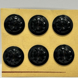 May include: Six black plastic buttons with a swirl design. The buttons are arranged in two rows of three on a brown card.