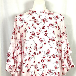 May include: A pink and white blouse with a floral print and ruffled sleeves.