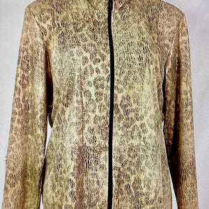 May include: A tan and brown patterned jacket with a black zipper closure. The jacket has a high collar and long sleeves. The pattern resembles a reptile skin. The jacket is displayed on a white mannequin.