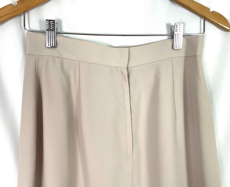 May include: A pair of beige high-waisted pants with a center back zipper and a straight leg.