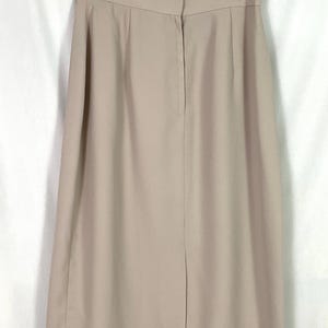 May include: A beige skirt with a back zipper closure. The skirt is knee-length and has a straight silhouette.