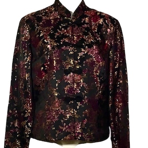 May include: A black silk jacket with a floral pattern in shades of gold, pink, and purple. The jacket has a mandarin collar and a button closure.