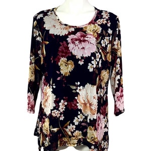 May include: A black sheer top with a floral print featuring pink, white, and yellow flowers. The top has a round neckline and 3/4 sleeves.