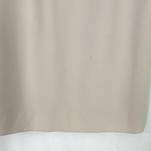 May include: A close-up of a light beige fabric with a small stain.