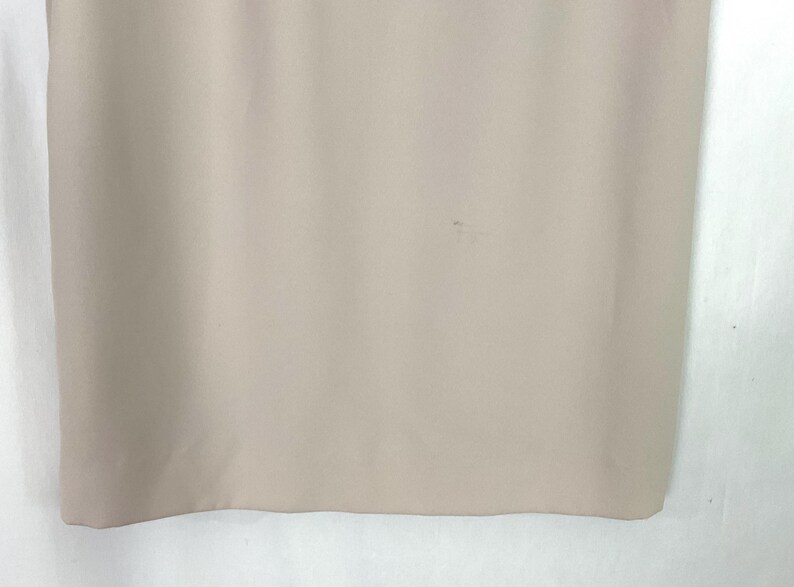 May include: A close-up of a light beige fabric with a small stain.