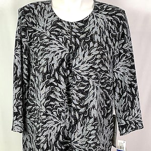 May include: Black and silver leaf-patterned jacket with a round neckline and three-quarter sleeves. The jacket has a button closure and a split front design. The fabric has a subtle shimmer, and the leaf pattern is detailed with shades of gray and silver.
