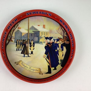 May include: A red metal tray with a blue and white image of George Washington and his troops at Valley Forge. The tray has the text "Valley Forge Beer - Scheidt's Rams Head Ale" around the rim.