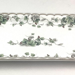 May include: White rectangular serving tray with a scalloped edge and a gold trim. The tray is decorated with a green and brown vine pattern.
