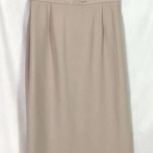 May include: A beige pencil skirt with a beaded floral design at the waistband.