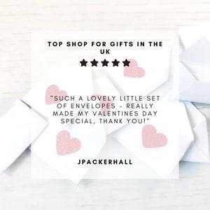 Peut inclure: Enveloppes blanches avec des c&oelig;urs roses scintillants. Le texte de l'image indique "TOP SHOP FOR GIFTS IN THE UK" et un avis client : "SUCH A LOVELY LITTLE SET OF ENVELOPES - REALLY MADE MY VALENTINES DAY SPECIAL, THANK YOU!"