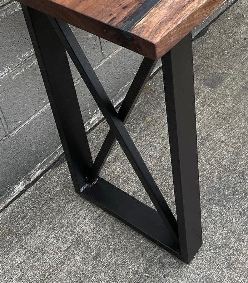 May include: Close-up of a black metal table leg with a geometric design. The leg is made of thick, sturdy metal and has a matte black finish.