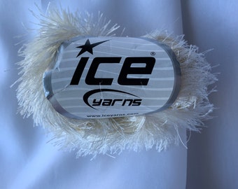 Puede incluir: Un ovillo de hilo blanco con textura esponjosa. El hilo está etiquetado con "ICE yarns" con un logotipo de estrella y la dirección del sitio web "www.iceyarns.com".