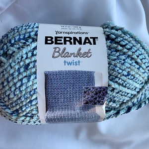 May include: A skein of Bernat Blanket Twist yarn in a blue and gray colorway. The yarn is 10.5 oz / 300 g and 228 yds / 208 m. The label shows a crocheted blanket in a blue color.