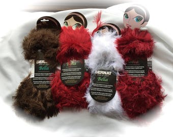 May include: Four skeins of yarn in different colors: brown, red, white, and red. The yarn is Bernat Bella, a soft and cozy yarn perfect for knitting or crocheting.