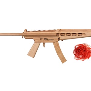 May include: A wooden toy gun with a red tip and a red rubber band. The gun is labeled "MODEL MP5 -  SPRENGBOXX".