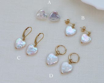 May include: A collection of heart-shaped pearl earrings in various styles. The earrings feature iridescent white pearls with gold-colored metal accents. Styles include stud, drop, and hoop earrings, all with a romantic theme.