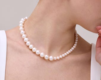 May include: A classic pearl necklace and matching stud earrings. The necklace features graduated pearls, transitioning from larger sizes at the front to smaller ones near the clasp. The earrings are simple, with a single pearl on each gold stud.