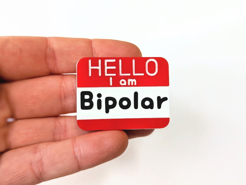 May include: Red name tag with white text that reads "Hello I am Bipolar".