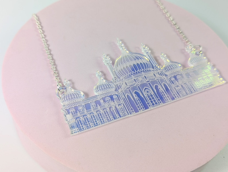 May include: A silver chain necklace with a white iridescent pendant shaped like the Brighton Pavilion, a famous landmark in Brighton, England.