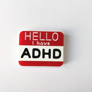 May include: Red name tag with white text that reads "HELLO I have ADHD".
