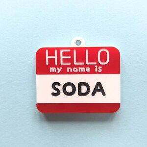 May include: Red and white name tag with the text "HELLO my name is SODA" printed in black.