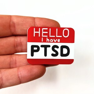 May include: Red name tag with white text that reads "Hello I have PTSD".