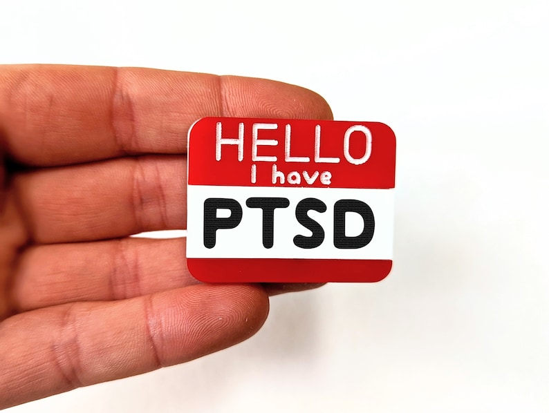 May include: Red name tag with white text that reads "Hello I have PTSD".